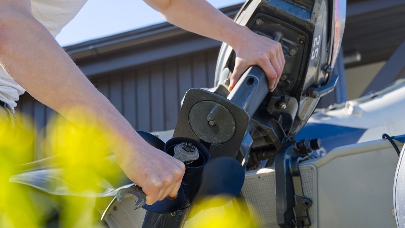 man changing propeller on outboard motor. Repairing outboard motor for boat, replacing screw.