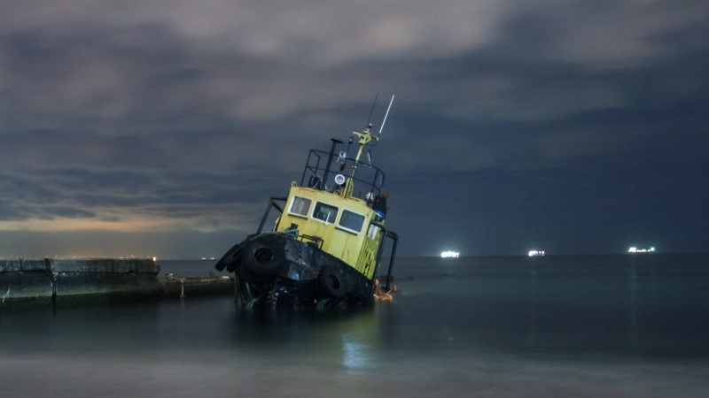 Tugboat ran aground, starry night sky with clouds.